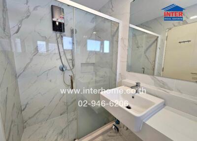 Modern bathroom with a glass shower enclosure, wall-mounted water heater, and sink with a mirror