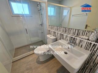 Modern bathroom with glass shower enclosure, toilet, and sink