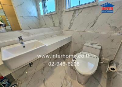 Modern bathroom with white sink, toilet, and marble tiles