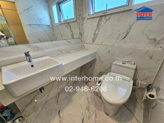 Modern bathroom with white sink, toilet, and marble tiles