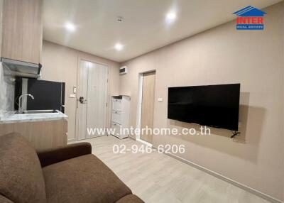 Living space with adjacent kitchenette and wall-mounted TV