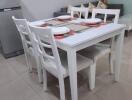 Dining area with a white table and chairs, adjacent to the living room