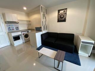 Well-lit studio apartment with living area, kitchen, and laundry