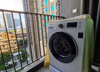 A balcony with a washing machine and a view of the surrounding buildings
