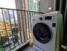 A balcony with a washing machine and a view of the surrounding buildings