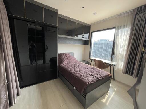 Modern bedroom with single bed, built-in wardrobe, and city view