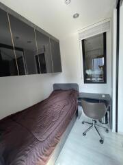 Modern bedroom with single bed, mounted storage cabinets, desk, and chair