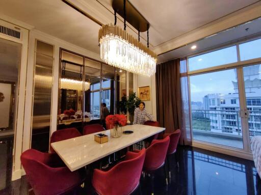 Elegant dining room with a large chandelier, marble table, and red chairs