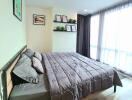 A spacious bedroom with a double bed, framed pictures on the wall, and large windows with curtains