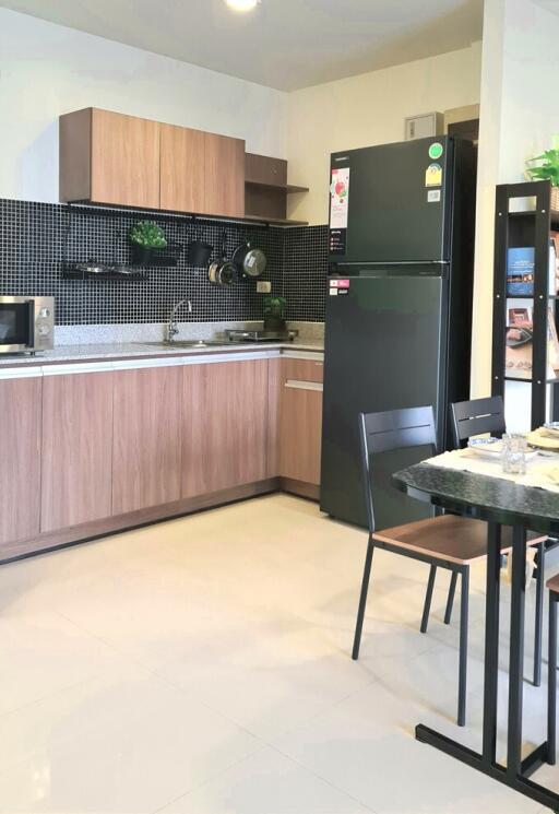 Modern kitchen with wooden cabinets, black fridge, and dining area