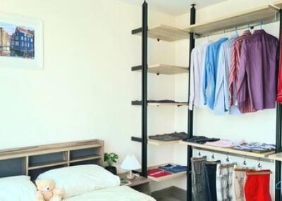 Bedroom with bed, shelving, and hanging clothes