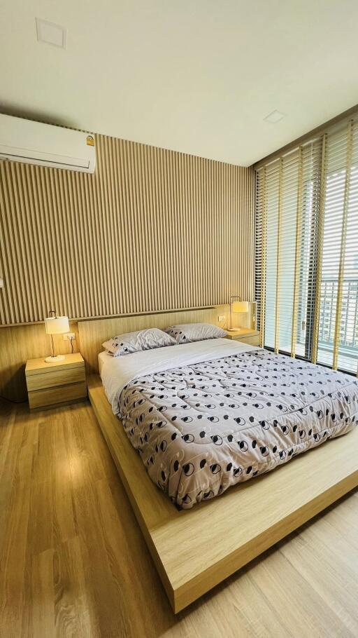 Modern bedroom with wooden flooring and large windows