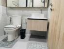 Modern bathroom with toilet, sink, mirror cabinet, and bath mats