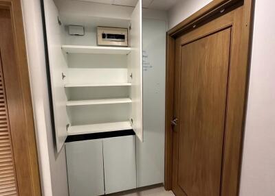 Utility closet with open cabinet doors showcasing shelves and an electrical panel