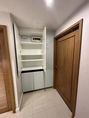 Utility closet with open cabinet doors showcasing shelves and an electrical panel