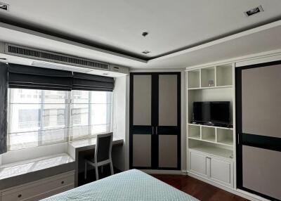 Modern bedroom with large window, built-in closets, and TV