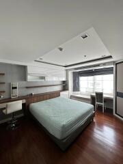 Modern bedroom with double bed, wooden floor, and study area