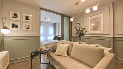 Living room with beige sofa, modern decor, and view into a bedroom