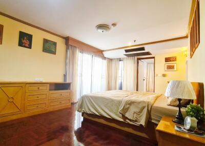 Spacious and well-lit bedroom with wooden furniture and large windows