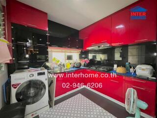 Modern kitchen with red cabinetry and washing machine