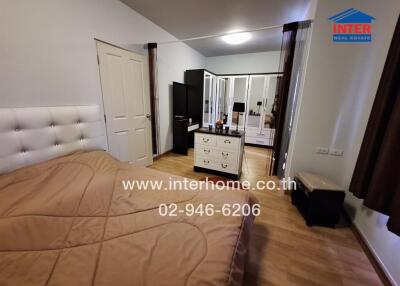 Bedroom with bed, wardrobe, dresser, and wooden flooring