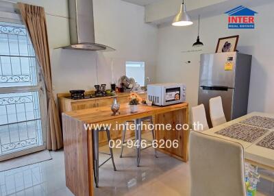 Modern kitchen with dining area featuring a wooden island, appliances, and a dining table