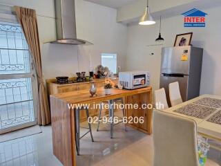 Modern kitchen with dining area featuring a wooden island, appliances, and a dining table