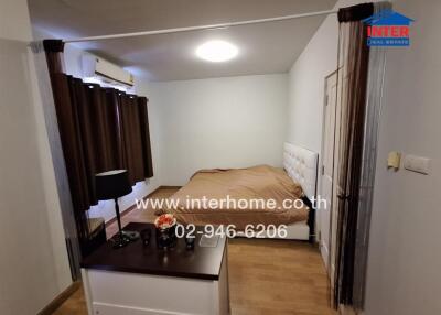 Spacious bedroom with a double bed, bedside table, air conditioning unit, and dark curtains.