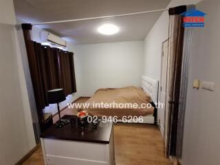 Spacious bedroom with a double bed, bedside table, air conditioning unit, and dark curtains.