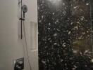 Modern bathroom shower area with dark and light contrasting tiles