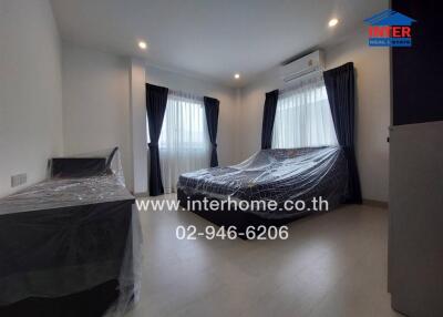 A spacious modern bedroom with furniture covered in plastic sheets in a property listed on the real estate portal.