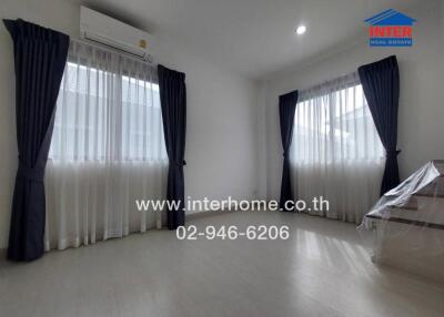 Spacious bedroom with large windows, curtains, and air conditioning.