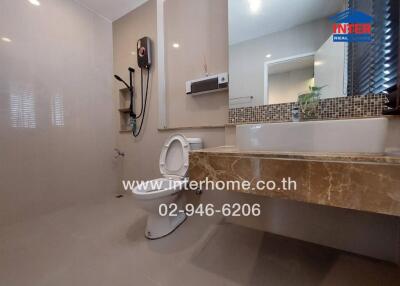 Modern bathroom with toilet, sink, water heater, and large mirror