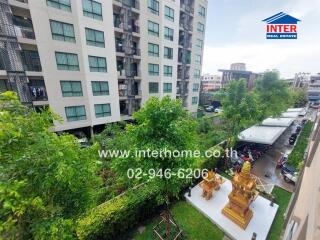 View of apartment building exterior with greenery and parking area