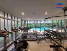 Fitness room with various exercise equipment and large windows showing a pool view