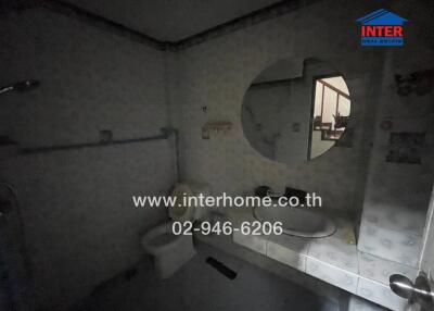 Dimly lit bathroom with round mirror and shower