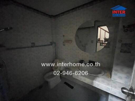 Dimly lit bathroom with round mirror and shower