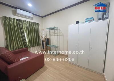 Small living room with red sofa, storage unit, and window with green curtains