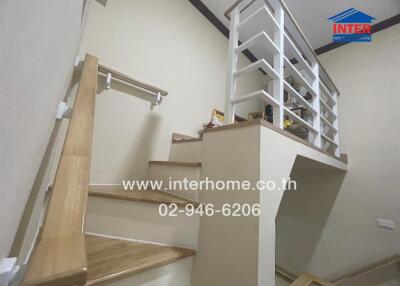 staircase area with wooden handrails and a small shelf