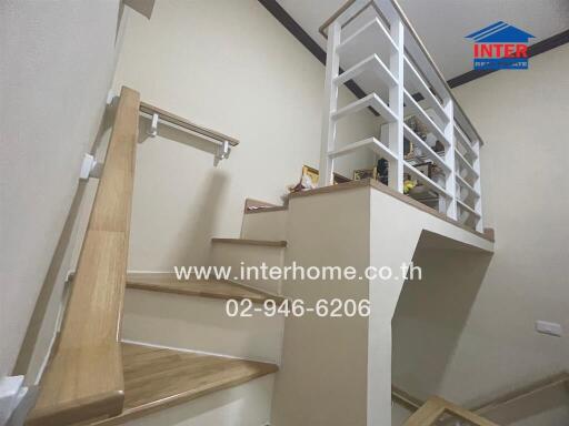 staircase area with wooden handrails and a small shelf
