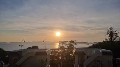 View of houses with ocean and sunset in the background