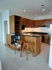 Modern kitchen with wooden cabinets, black countertops, and bar stools