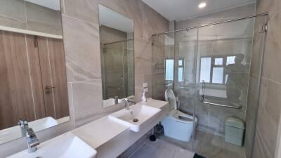 Modern bathroom with double sinks, glass shower door, and large mirrors