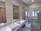 Modern bathroom with double sinks, glass shower door, and large mirrors