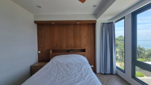 Bedroom with wooden accent wall and large window with ocean view