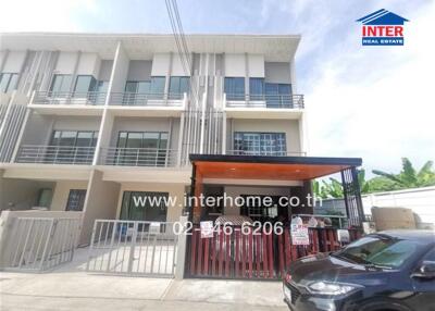 Front view of a modern townhouse with three levels, a gated parking area, and a balcony