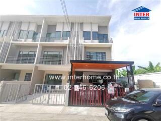 Front view of a modern townhouse with three levels, a gated parking area, and a balcony