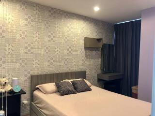 Modern bedroom with decorative wallpaper, bed, and side table