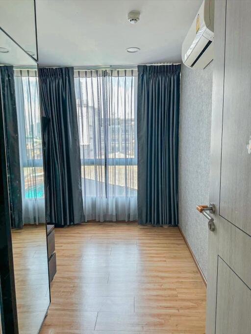 Well-lit bedroom with hardwood floor and large window