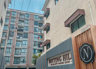 Exterior view of Notting Hill condominium with entrance gate and signage